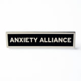 Rectangle Enamel Pin that says ANXIETY ALLIANCE.  Silver text and outline on black enamel background