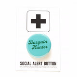 Round blue colored pinback button which reads BARGAIN HUNTER in a dark green vintage font, on two lines. The button is on a white Social Alert Button backing card with a black plus sign at the top. 