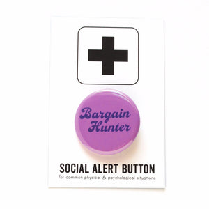 Round violet-purple colored pinback button which reads BARGAIN HUNTER in a dark purple vintage font, on two lines. The button is on a white Social Alert Button backing card with a black plus sign at the top. To the right is the same button in two different color ways. The top right is a golden orange-brown with toffee color text, and below is a pale cyan button with dark green text. Overall vintage vibe.