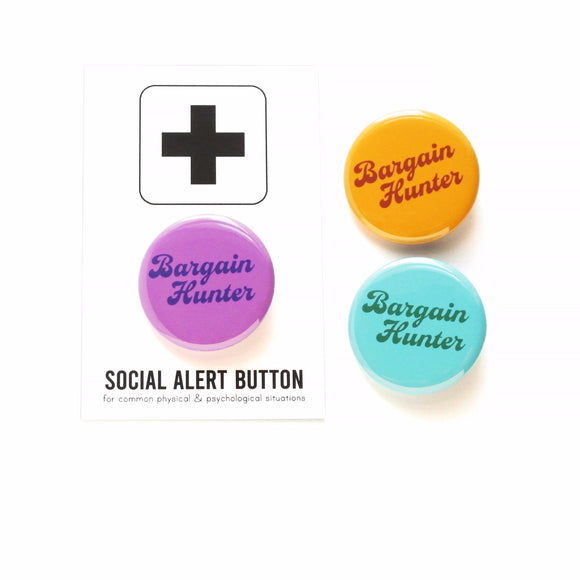 Round violet-purple colored pinback button which reads BARGAIN HUNTER in a dark purple vintage font, on two lines. The button is on a white Social Alert Button backing card with a black plus sign at the top. To the right is the same button in two different color ways. The top right is a golden orange-brown with toffee color text, and below is a pale cyan button with dark green text. Overall vintage vibe.