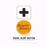 Round caramel colored pinback button which reads BARGAIN HUNTER in a chocolate brown vintage font, on two lines. The button is on a white Social Alert Button backing card with a black plus sign at the top. 