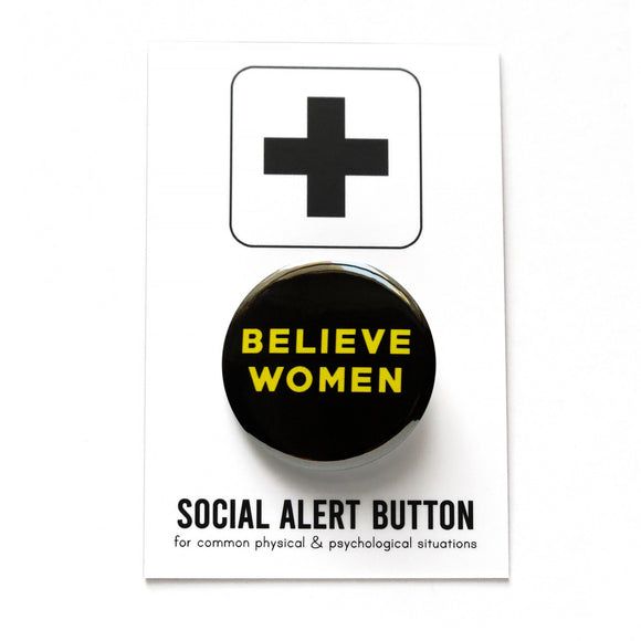 Round black pinback button that reads BELIEVE WOMEN in yellow san serif text. The button is pinned to a Social Alert Button backing card.