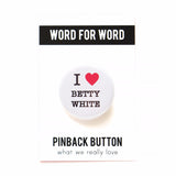 A shiny, round white pinback button with black serif text and a read heart, the button reads: I LOVE BETTY WHITE, with love being illustrated by a red heart. The button is on a black & white backing card that reads the brand name WORD FOR WORD at the top, and Pinback Button on the bottom