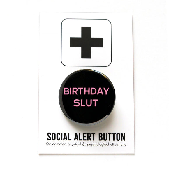 Round black pinback button that reads BIRTHDAY SLUT in thin yellow san serif text. The button is pinned to a Social Alert Button backing card.