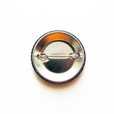 A metal pin back button, back of badge