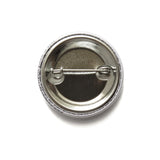 A metal pinback button, backside of badge