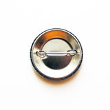 Metal pinback button, view of the backside used to pin onto clothing or bag.