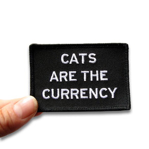 Rectangle patch that says CATS ARE THE CURRENCY.  White text on a black background.