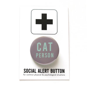Round gray pinback button that reads CAT PERSON in mint green san serif text. Button is on a Social Alert Backing card with a black plus sign at the top.