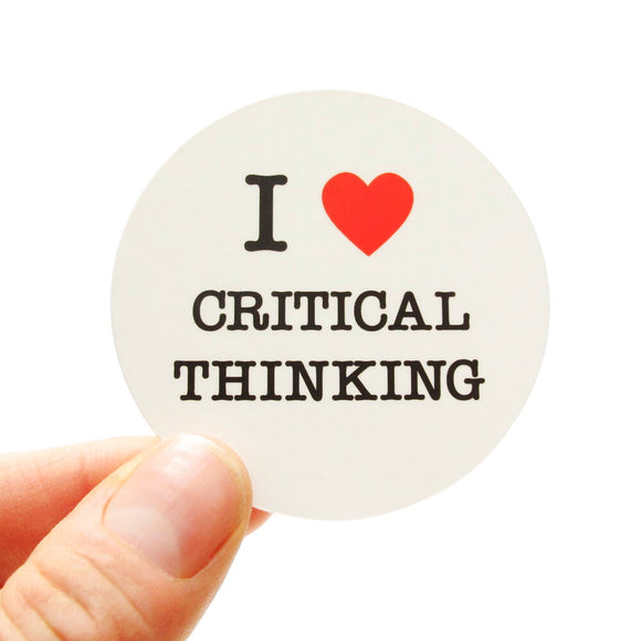 Round die-cut sticker that says I LOVE CRITICAL THINKING. The text is black with a red heart signifies the word love. The background is white.