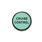 Round enamel pin that says CRUISE CONTROL.  Gunmetal text and outline on a aqua background