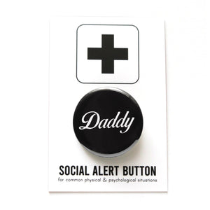 Round shiny black pinback button with a white script font that reads DADDY.  On a white backing card, black plus sign at the top. Below reads: Social Alert Button, with tiny text beneath it which says, for common physical & psychological situations