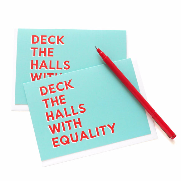 Holiday greeting cards that say DECK THE HALLS WITH EQUALITY.  Red text on minty green-blue background. Image features 2 cards with a red pen laying across the upper corner