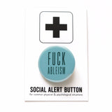 A pale turquoise shiny finback button that reads Fuck Ableism in a dark teal color, in a condensed sans serif font.  The pinback button is on a white backing card with a thick plus sign at the top of the card. On the bottom it reads Social Alert Button, for common physical & psychological situations.