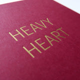 Burgandy greeting card that says HEAVY HEART. Close up of the gold hot foil pressed text.