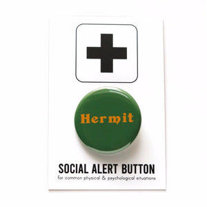 Shiny round dark green button with goldenrod serif text that reads: HERMIT. Hermit button is on a black & white branded card with a large plus sign at the top, and reads Social Alert Button at the bottom of the card, beneath the button