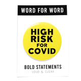 Big round neon yellow pinback button reads HIGH RISK FOR COVID in bold black text. On a white backing card, WORD FOR WORD  brand across the top. Bold StatementS, Loud & Clear at the bottom of the card