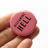 Round rosy mauve pinback with splatter dots button reads HISTAMINE HELL in black text.  Button is held in a white hand.