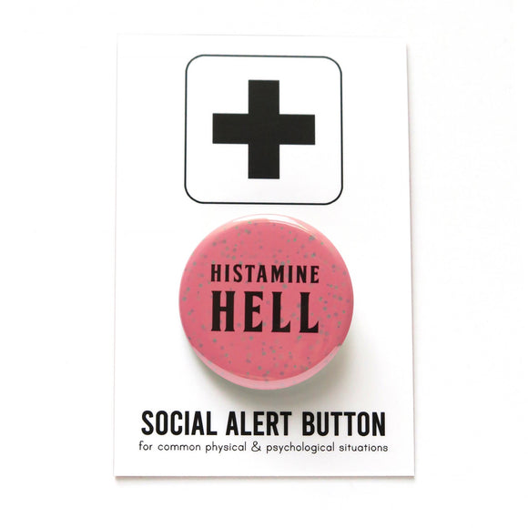 Round rosy mauve pinback with splatter dots button reads HISTAMINE HELL in black text. On a white backing card, black plus sign at the top. Below reads: Social Alert Button, with tiny text beneath it which says, for common physical & psychological situations