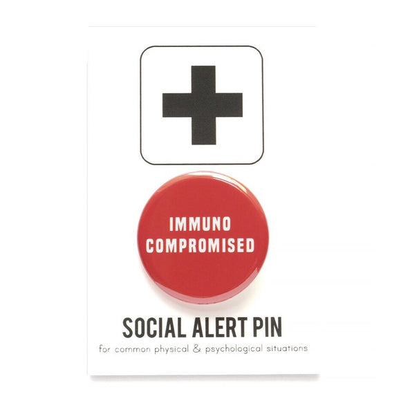 Round pinback button that says IMMUNOCOMPROMISED. White text on a red background.  Affixed to a Social Alert Pin backing card.