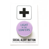 A round lavender pinback button that reads LIGHT IN THE LOAFERS in forest green. Button is on a Social Alert Button backing card.