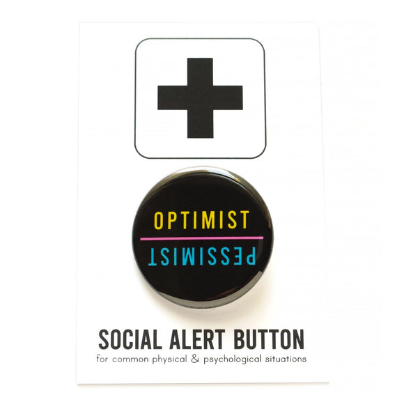 Round pinback buttons that says OPTIMIST, in yellow text, in one direction, and PESSIMIST, in blue text,  in the opposite direction.  Text is on a black background. The button is pinned to a Social Alert Button backing card.