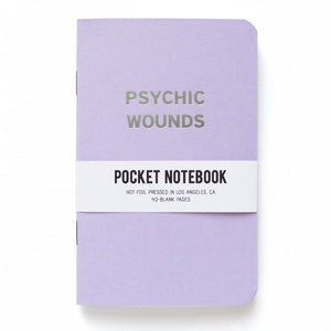 Lavender pocket notebook that says PSYCHIC WOUNDS in silver text.