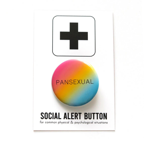 Round pinback button with a pink yellow blue diagonal ombre that reads PANSEXUAL in a thin black san serif font.  On a white backing card, black plus sign at the top. Below reads: Social Alert Button, with tiny text beneath it which says, for common physical & psychological situations