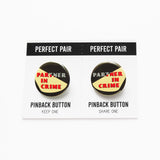 Two pinback buttons on a backing card with a center perforation to tear & share with a friend. Buttons read PARTNER IN CRIME, with a flash light yellow shape across the text.