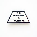 Trapezoid shaped pin that says THE PERSONAL IS POLITICAL. Gunmetal silver text  on a white enamel background.
