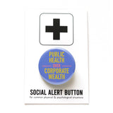 A round pinback button with a scrubs blue-purple background that reads PUBLIC HEALTH OVER CORPORATE WEALTH in yellow and neon red. Button is on a Social Alert Button backing card.