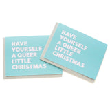 Holiday greeting cards that say HAVE YOURSELF A QUEER LITTLE CHRISTMAS.  White text on a icy blue background.
