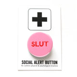 Round bright pink pinback button that reads SLUT in a rounded red font. Pinback button is on Social Alert Button Backing Card