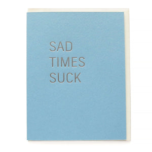 Powder blue greeting card that says SAD TIMES SUCK in silver hot foil pressed text.