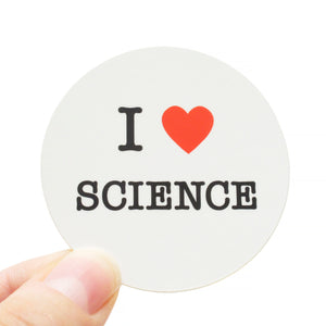 Round die-cut sticker that says I LOVE SCIENCE. The text is black with a red heart signifies the word love. The background is white.