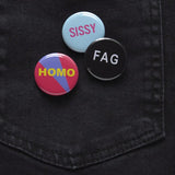 A black denim back pocket with three pinback buttons: HOMO, SISSY and FAG