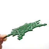 A side view of a green glitter acrylic holiday ornament, showing the eighth inch thickness of the large rather flat holiday ornament for hanging on a tree or wall.