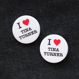 Two round white I heart Tina Turner buttons with a red hearts, on the background of black denim