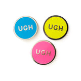 Round enamel pin the says UGH.  In three different color choices.  Silver text and outline with a neon blue enamel background. Gunmetal silver text and outline with a neon yellow enamel background. And silver text and outline on a neon pink enamel background.