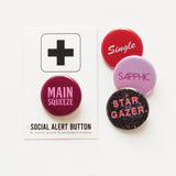 Round magenta-maroon pinback button that reads MAIN SQUEEZE in a light pink font. Button is on a Social Alert Button backing card. 3 other pinback buttons are overlapping on the right side: A bright red pinback back that reads SINGLE in white text.  A pink hombre pinback that reads SAPPHIC in magenta text. And a black with a photos of outer space that reads STAR GAZER in salmon pink text.
