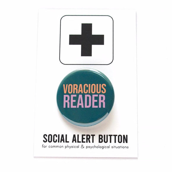 Round teal colored pinback button which reads Voracious Reader in sans serif font. Voracious is in peach, Reader is a larger word and in lavender. The button is on a white Social Alert Button backing card with a black plus sign at the top.