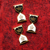 Three hour glass shaped pins that say A WOMAN'S WORK IS NEVER DONE, on a red denim background.