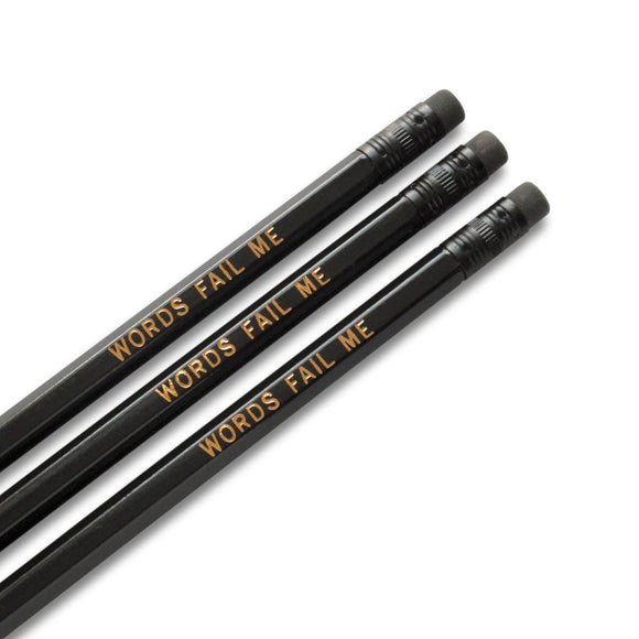 Three black pencils, with black ferrules and erasers, hot-foil pressed with the words  WORDS FAIL ME in copper foil.