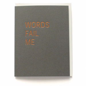 Dark gray vertical greeting card with a thin san serif font stamped in copper hot foil , reading WORDS FAIL ME, on a white background