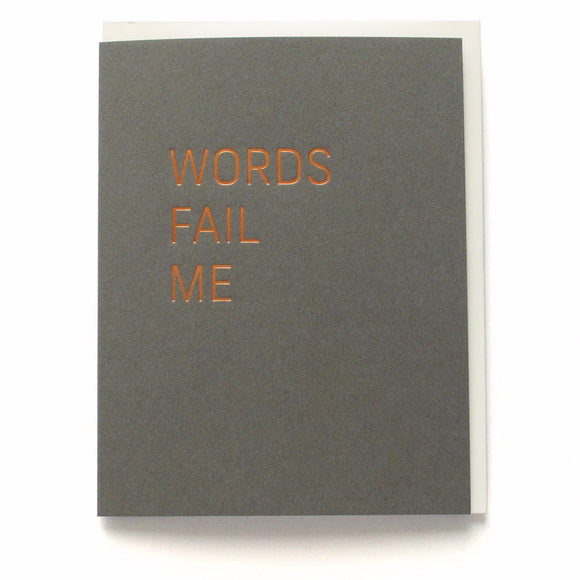 Dark gray vertical greeting card with a thin san serif font stamped in copper hot foil , reading WORDS FAIL ME, on a white background